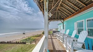 A beachside porch with a view of the ocean, white Adirondack chairs, and a turquoise building. - The Oceanic, Beachfront Oasis*Sleeps 20*Hot Tub (Crystal Beach)