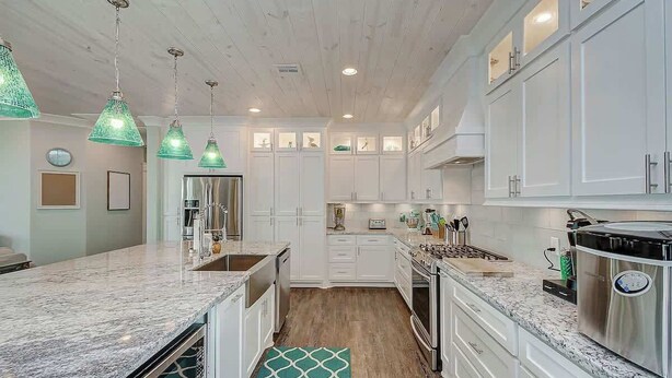 A modern kitchen with white cabinetry, granite countertops, and pendant lighting. - The Oceanic, Beachfront Oasis*Sleeps 20*Hot Tub (Crystal Beach)