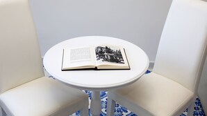 A small round table with a book and a photograph on it, surrounded by two white chairs. - King Room with Balcony (Sorrento)