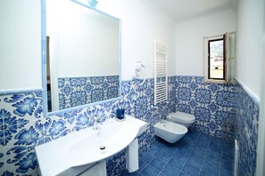 A bathroom with a sink, toilet, and bidet, featuring blue and white patterned tiles. - King Room with Balcony (Sorrento)