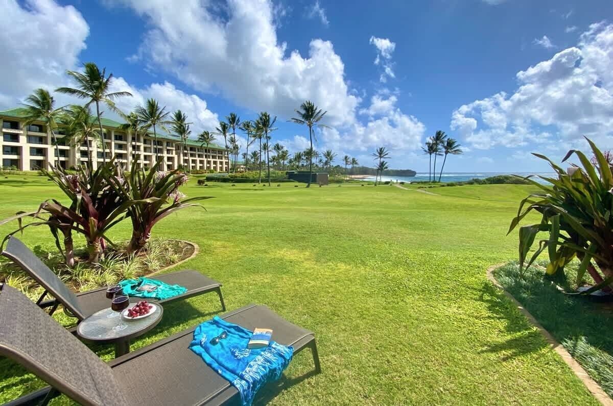 Een golfbaan met loungestoelen en een hotel in de verte.