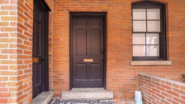 A brick building with a dark brown door and a window with blinds. - Minimalist Modern Suite Near German Village (Columbus)