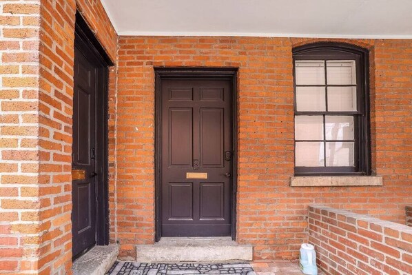A brick building with a dark brown door and a window with blinds. - Minimalist Modern Suite Near German Village (Columbus)