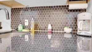 A kitchen with a hexagonal tile backsplash, a coffee maker, and a sink.