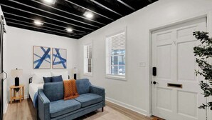 A modern living room with a sofa, a bed, and artwork on the wall.