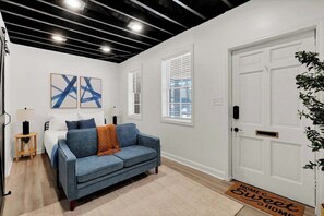 A modern living room with a sofa, a bed, and artwork on the wall.