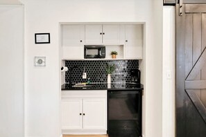 A compact kitchen with white cabinets, a black microwave, and a black dishwasher.