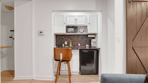 A compact kitchen with white cabinets, a microwave, and a coffee maker.