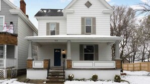 Une maison à deux étages avec un porche à l’avant, une cheminée et le numéro « 919 » sur la porte.