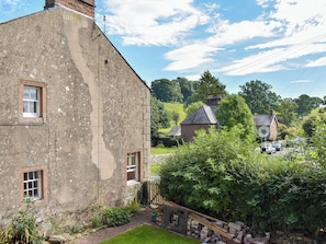 A stone building with a window, a brick chimney, and a sign reading 'STAFFORD' in the background. - Staffield Cottage - UK35714 (Staffield, near Penrith)