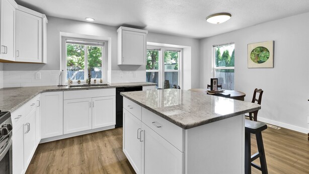 Una cocina moderna con armarios blancos, una isla grande y un comedor con mesa y sillas.