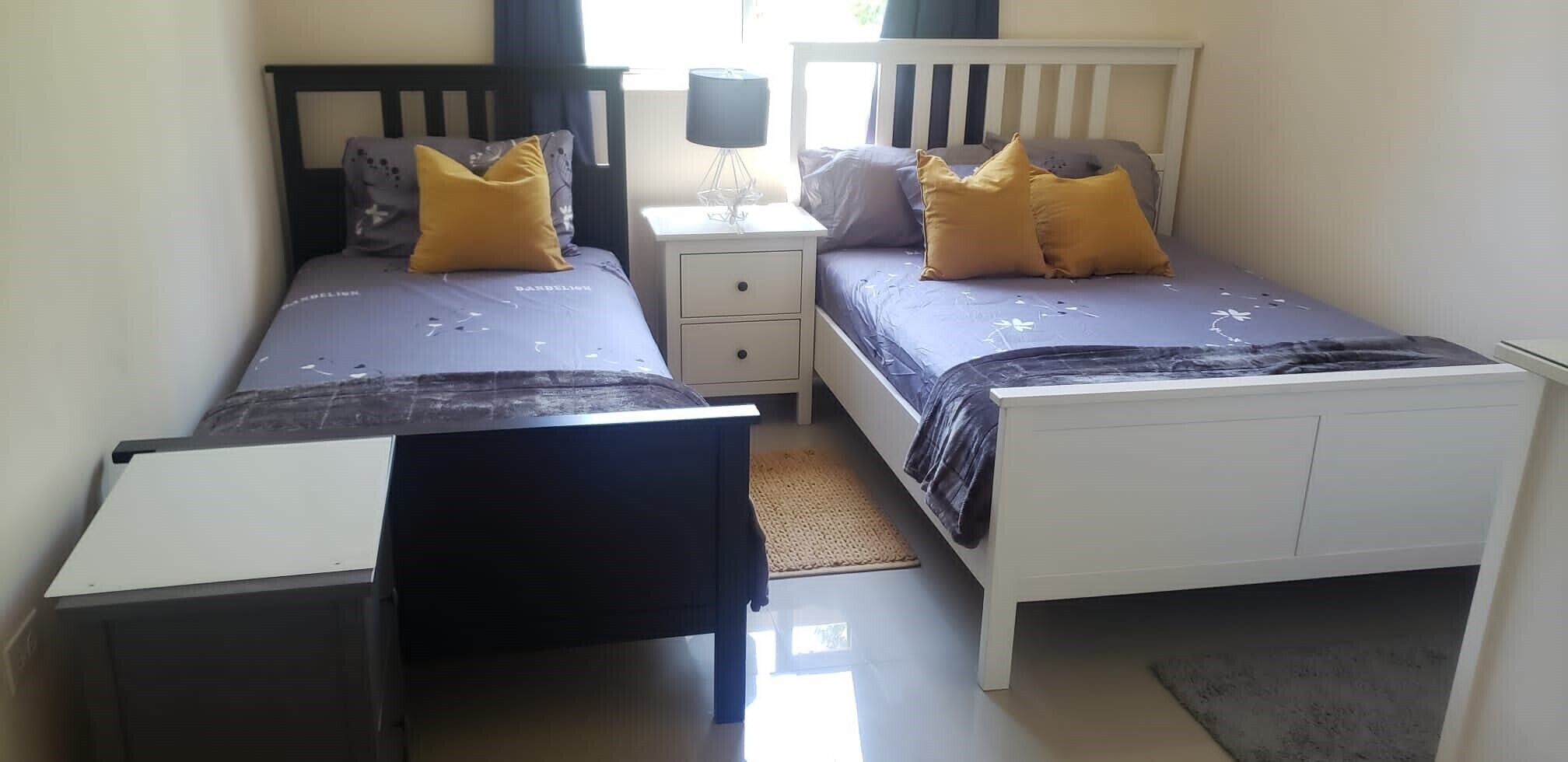 Quarto com duas camas, uma mesa de cabeceira e uma escrivaninha.