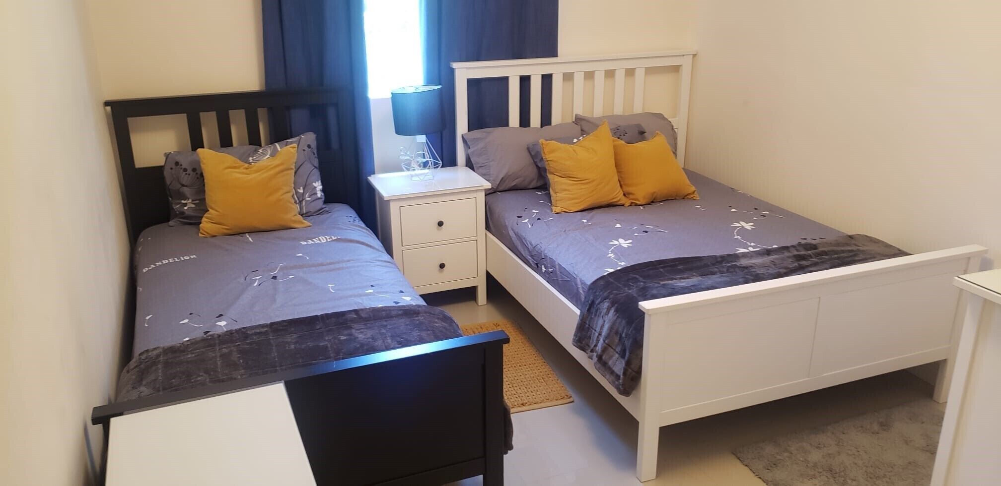 A twin bedroom with two beds, each with a headboard, a bedside table, and a lamp.