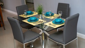 Ein Esstisch, gedeckt mit blauen Tellern, Besteck und einem kleinen Blumentopf.