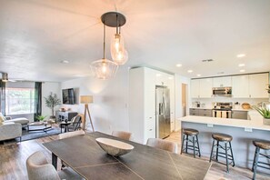 A modern kitchen with white cabinets, stainless steel appliances, and a central island with stools. - Fire Pit, Heated Pool: Central Tempe Escape! (Tempe)
