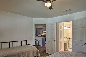 Une chambre avec un lit, un ventilateur de plafond et une vue sur un coin cuisine.