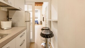 Une petite cuisine comprenant un grille-pain, un évier et un tabouret de bar.