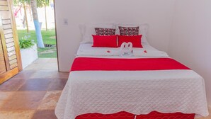A neatly made bed with a red and white bedspread, two red pillows, and a white quilt. - Pousada Cenário Ideal - Paradise is very close to you! (Icapuí)