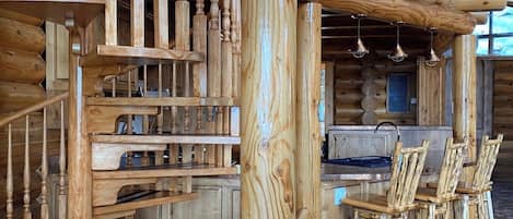 Un interior de madera con una escalera, una zona de cocina y un espacio de estar.