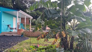 Una casa con facciata blu, un portico con sedie e un giardino con rocce e piante.