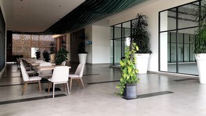 A modern lobby with a seating area, large potted plants, and a glass entrance. - Bell Suite Sepang KLIA Kota Warisan (Sepang)