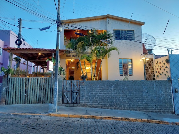 A two-story house with a balcony, a gated entrance, and a stone wall.