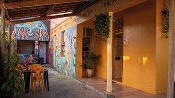 A covered outdoor area with a mural, a table with chairs, and a potted plant.