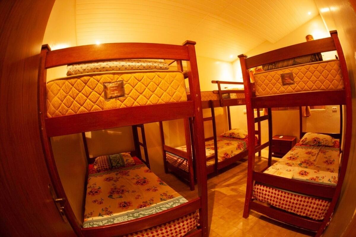 A room with bunk beds, wooden headboards, and a tiled floor.