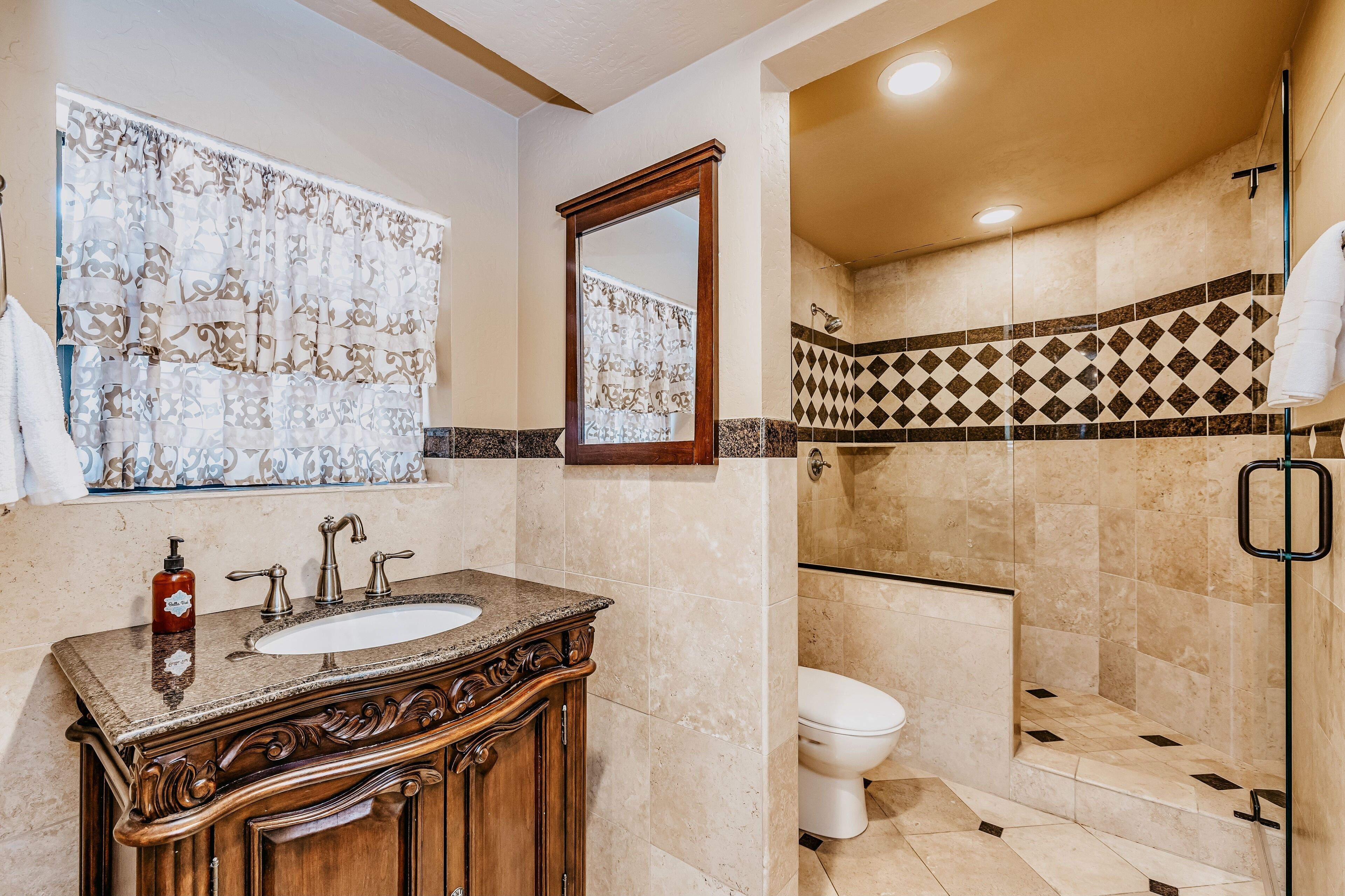 Un baño con lavamanos, espejo, ducha e inodoro.