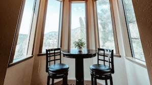 A dining area with a round table and two chairs, large arched windows, and a chandelier. - PARADISE! Family Reunions, Business Retreats, Vacations (Flagstaff)