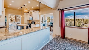 A modern kitchen with a granite countertop, white cabinets, and pendant lighting. - PARADISE! Family Reunions, Business Retreats, Vacations (Flagstaff)