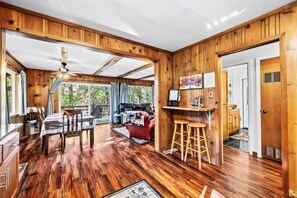 L’intérieur d’un chalet en bois comprend un coin repas, un bar et un espace salon avec vue sur l’extérieur.