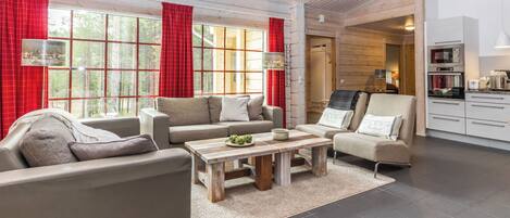 A spacious living room with a sofa set, a coffee table, and a kitchen area with modern appliances.