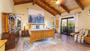 A spacious bedroom with a wooden bed, a large window, and a view of the outdoors. - Yosemite Lodge • Indoor pickleball, Basketball, Hot Tub, Game Room & EV (Oakhurst)