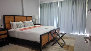 A modern hotel room with a bed, bedside tables, a lamp, and a window with curtains.