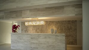 Un área de recepción de diseño moderno, con una pared de mármol y una mesa de recepción de color claro.