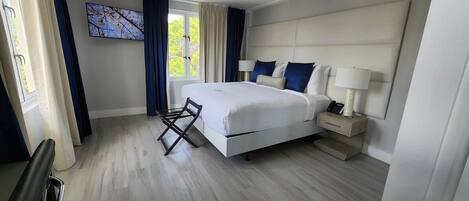 Et moderne hotelværelse med en stor seng, et sengebord med lampe, og udsigt til det fri.