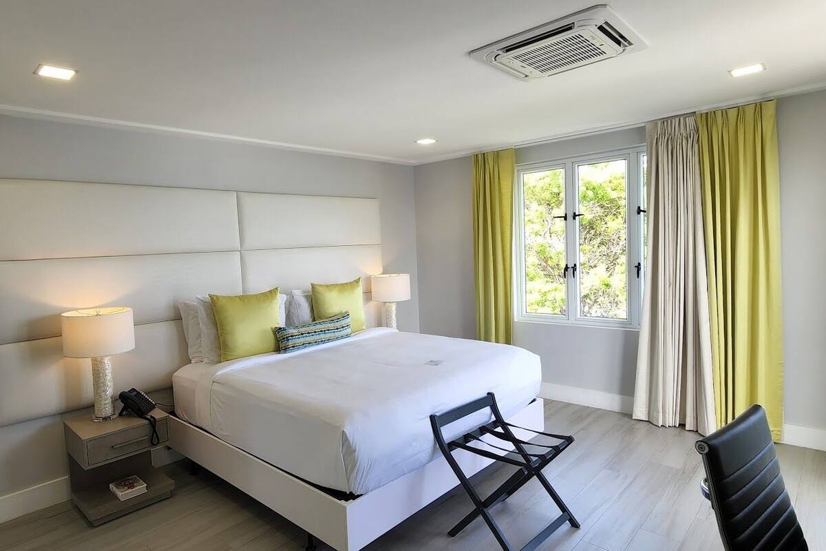 Un dormitorio moderno con una cama grande, lámparas de noche, una mesita de noche y una ventana con cortinas.