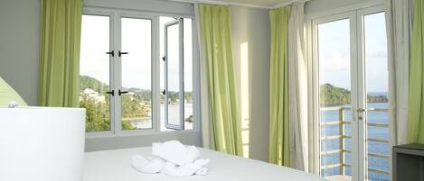 A hotel room with a bed, a window with curtains, and a view of a body of water.