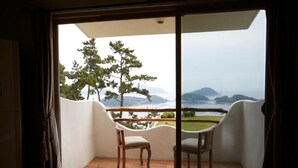 Een balkon met twee houten stoelen en uitzicht op een bergachtig landschap.