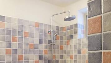 Une salle de bain avec des toilettes, une douche et un mur carrelé.