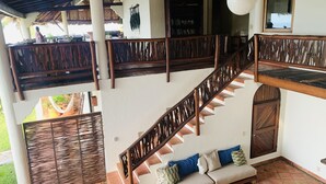 Un escalier en bois à plusieurs niveaux, avec un canapé et des coussins sur la petite plateforme inférieure.