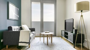 A modern living room with a grey sofa, a small round table, a flat-screen TV, and a floor lamp.