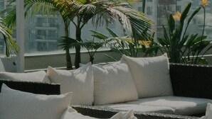 A balcony with a sofa, cushions, and potted plants.