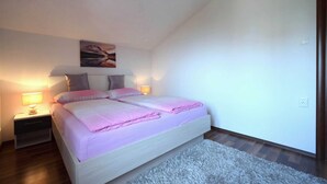 Ein Schlafzimmer mit Bett, Nachttischen, einer Lampe, einem Gemälde und einem Teppich.