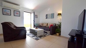 Ein Wohnzimmer mit einer Couch, einem Sessel, einem Couchtisch und einer TV-Bank.