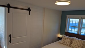 Un dormitorio con una cama, un divisor corredizo blanco, una ventana con vistas y una luz en el techo.