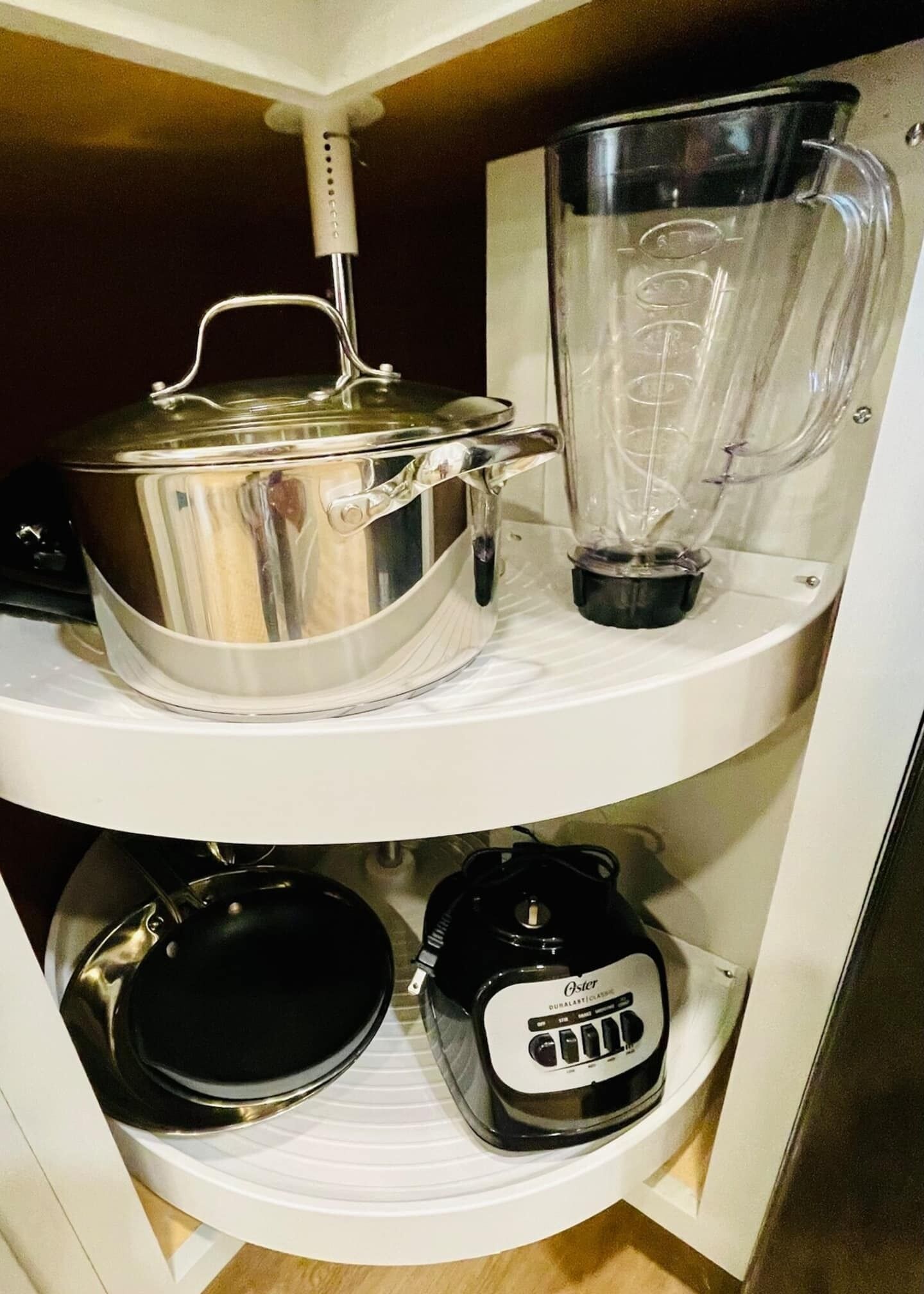 Une étagère de cuisine avec une casserole en acier inoxydable, un mixeur et une machine à café.