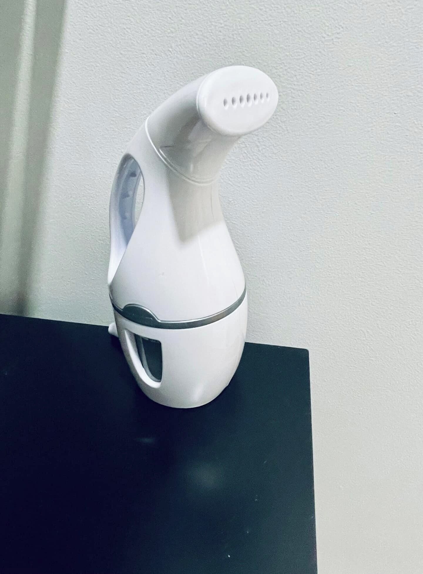 Una tetera eléctrica blanca sobre una encimera negra, frente a una pared blanca.