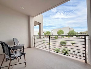 Ein Balkon mit Blick auf ein Gebäude und eine angelegte Grünfläche.